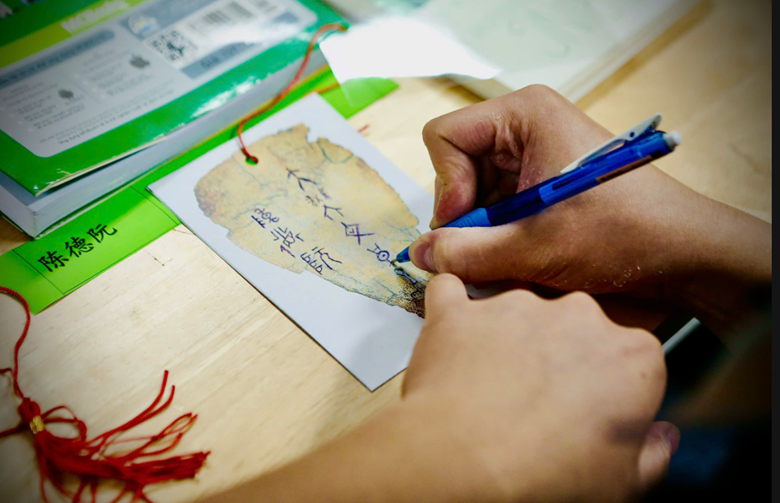 A person writing on a piece of paper
AI-generated content may be incorrect.