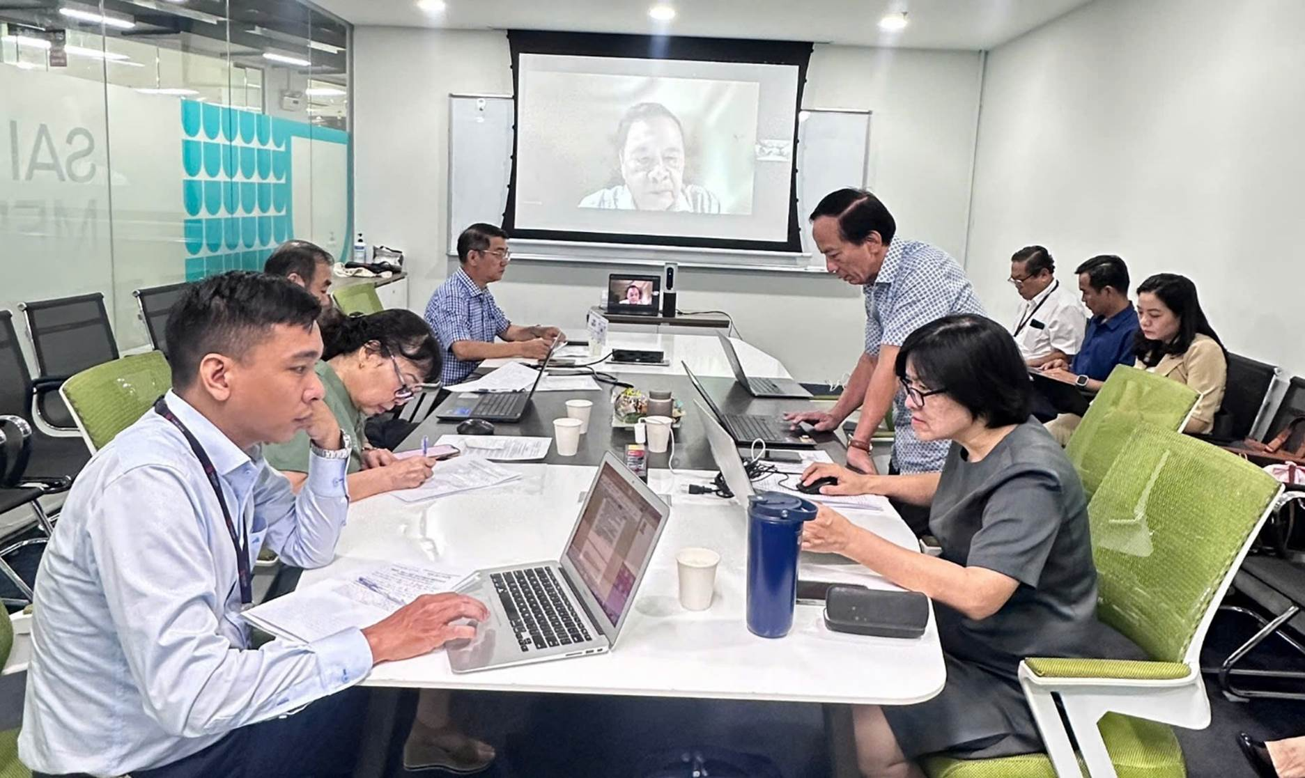 A group of people sitting at a table using laptops

Description automatically generated
