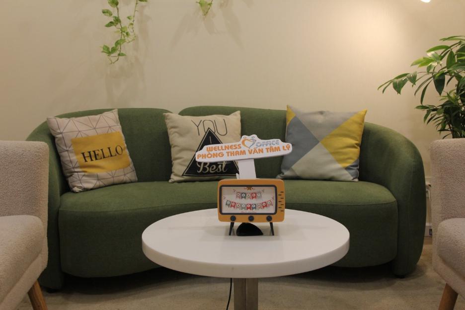 A green couch with pillows on a white table
Description automatically generated