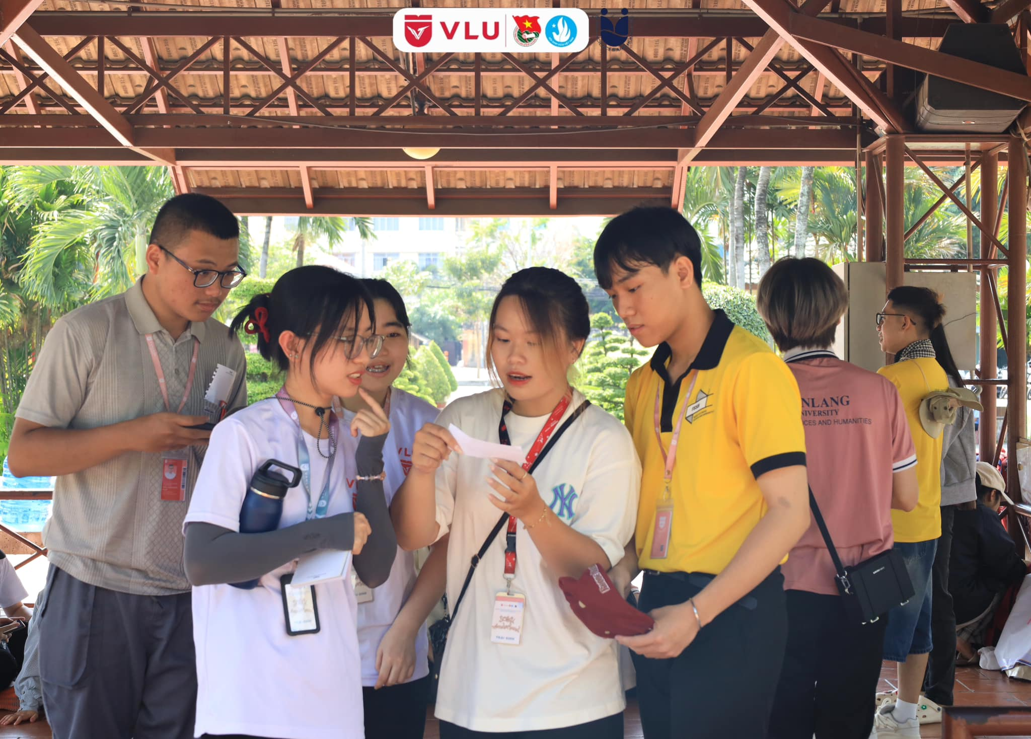 A group of people standing under a canopy looking at a piece of paper

Description automatically generated